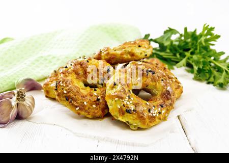 Curd and cheese bagels with garlic and herbs on paper against the background of a white wooden board Stock Photo