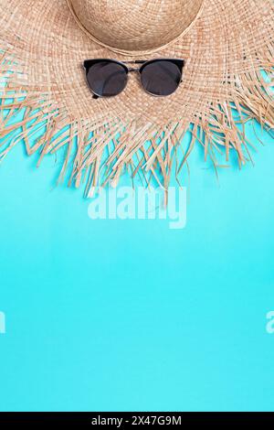 Straw hat with wide fields and sunglasses on blue background with copy space Stock Photo