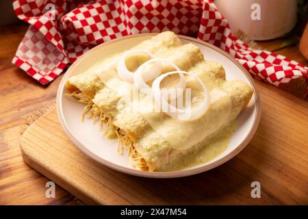 Mexican food. Enchiladas with creamy green sauce filled with shredded chicken meat and covered with melted cheese, in Mexico they are called Swiss Enc Stock Photo