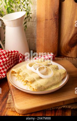 Mexican food. Enchiladas with creamy green sauce filled with shredded chicken meat and covered with melted cheese, in Mexico they are called Swiss Enc Stock Photo