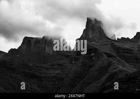 Ominous black and white view of mist surrounding the sentinel, the western buttress of the Amphitheatre, in the Drakensberg mountains of South Africa. Stock Photo