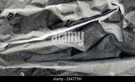 Black crumpled and creased plastic poster texture background . Stock Photo