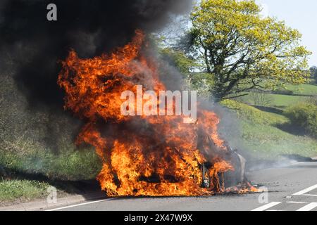 car on fire at the side of the road - UK Stock Photo