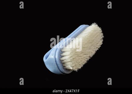 A clothes brush with plastic bristles lies on a black background. Stock Photo
