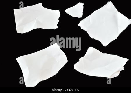 On a black background, four clean white paper sheets lie chaotically. They are creased and their edges are uneven. Stock Photo
