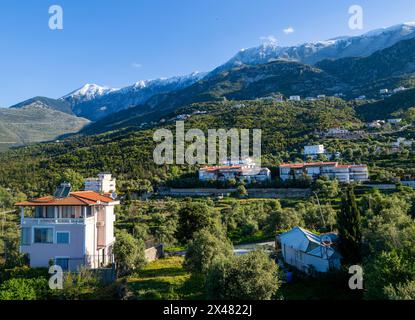 Snow capped peaks including Mount Cika rising above hillside village, Palase, near Dhermi, Albania Stock Photo