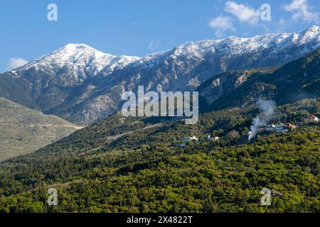 Snow capped peaks including Mount Cika rising above hillside village, Palase, near Dhermi, Albania Stock Photo