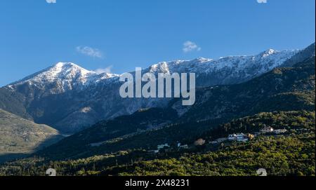 Snow capped peaks including Mount Cika rising above hillside village, Palase, near Dhermi, Albania Stock Photo