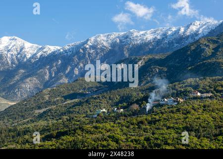 Snow capped peaks including Mount Cika rising above hillside village, Palase, near Dhermi, Albania Stock Photo