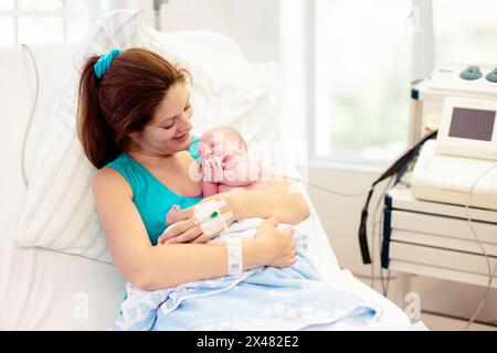 Mother giving birth to a baby. Newborn baby in delivery room. Mom holding her new born child after labor. Female pregnant patient in a modern hospital Stock Photo