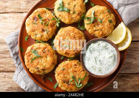 Chickpea Fritters with garlic, fresh herbs, spices served with dipping yogurt sauce close-up in plate on the table. Horizontal top view from above Stock Photo
