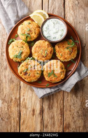 Vegetarian chickpeas fritters with garlic herb yogurt sauce close-up in plate on the table. Vertical top view from above Stock Photo