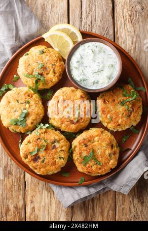 Chickpea fritters with tzatziki sauce close-up in a plate on a wooden table. Vertical top view from above Stock Photo