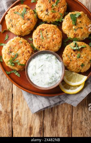 Comfort food Chickpea fritters with tzatziki sauce close-up in a plate on a wooden table. Vertical top view from above Stock Photo