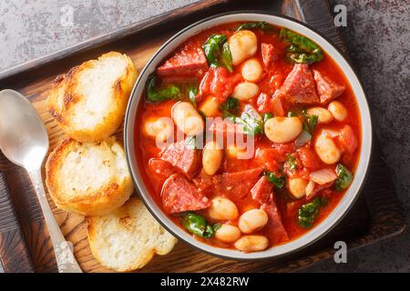 Spanish stew of butter beans, chorizo and spinach in tomato sauce close-up in a bowl on the table. Horizontal top view from above Stock Photo