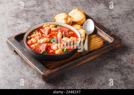 Spicy stew of lima beans, chorizo and spinach in tomato sauce close-up in a bowl on the table. Horizontal Stock Photo