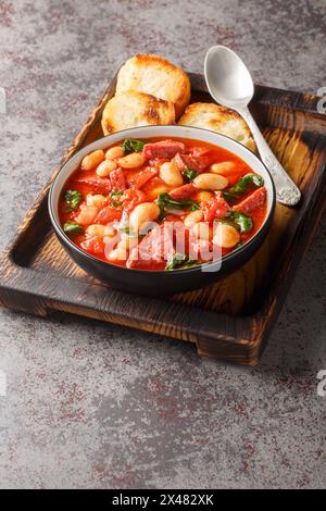 Slow cooked stew of butter beans, chorizo and spinach in tomato sauce close-up in a bowl on the table. Vertical Stock Photo