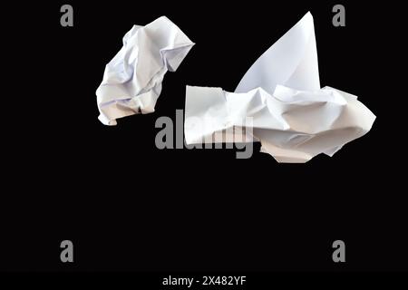 On a black background, crumpled paper sheets lie chaotically. Stock Photo