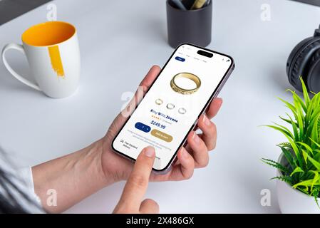 Woman using smartphone to shop for zircon ring online. Convenience meets elegance as she browses jewelry on ecommerce store Stock Photo