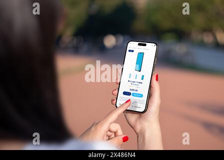 Buying gadgets online, exploring modern shop interface with smartphone prices. Woman searches page using her smartphone for convenience Stock Photo