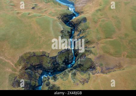 Between the hills in Iceland flows winding blue river, branch of mountain streams. View from drone Stock Photo