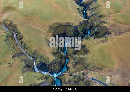 Between the hills in Iceland flows winding blue river, branch of mountain streams. View from drone Stock Photo