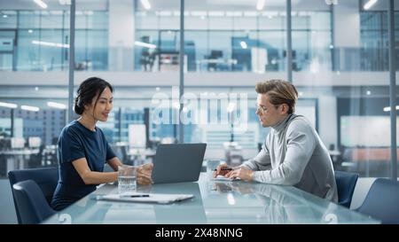 Multiethnic Diverse Office Conference Room Meeting: Team of Two Creative Entrepreneurs Talk, Discuss Growth Strategy. Stylish Young Businesspeople work on Investment and Marketing Projects. Stock Photo