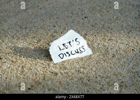 Let's Discuss handwritten text on the sand background. Stock Photo