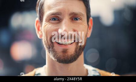 Portrait of a Happy Handsome Bearded Man in Casual Clothes Standing on the Street Looking at Camera, Smiling. Stylish Young Adult or Early Middle Aged Male with Beard. Blurred Dig City in Background Stock Photo