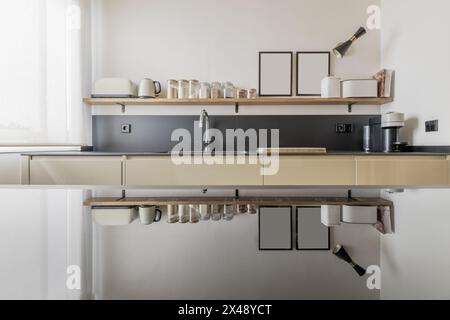A front of a kitchen with shelves full of condiments and their reflection in a glass ceramic hob Stock Photo