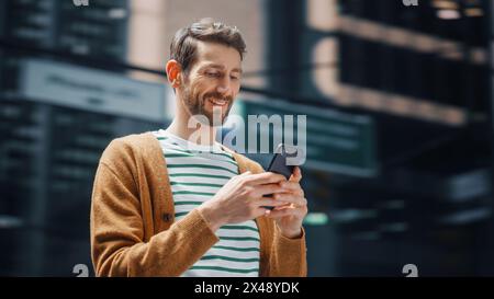 Street Shot: Portrait of Caucasian Man Using Smartphone in the Big City. Creative Professional Using Mobile Phone App for e-Commerce Online Shopping. Blurred Background. Stock Photo
