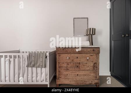 A children's bedroom with a white wooden crib and a vintage chest of drawers Stock Photo
