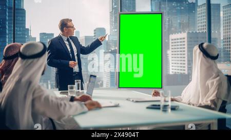 International Manager Holds Meeting Presentation for Saudi Business Partners. Specialist Uses Whiteboard with Vertical Green Screen Mock Up Display. Saudi, Emirati, Arab Office Concept. Stock Photo
