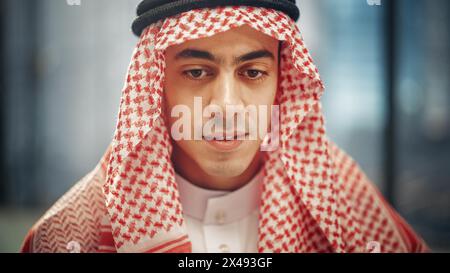 Portrait of Young Successful Arab Businessman in Traditional Outfit Gently Smiling, Wearing White Kandura and Black Agal Keeping a Ghutra in Place. Saudi, Emirati, Arab Businessman Concept. Stock Photo
