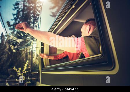 Caucasian Couple Enjoying Their Time in a RV Camper Van. Opening Side Window. Stock Photo