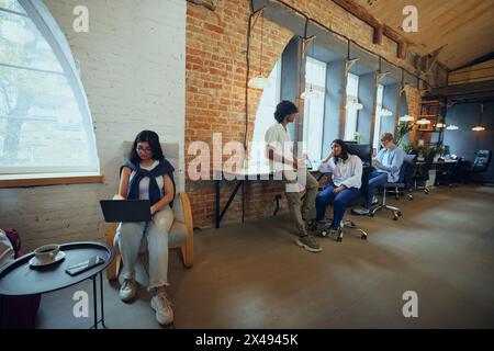 Young entrepreneurs and students in co-working space working and cooperating. Cozy, comfortable professional atmosphere Stock Photo