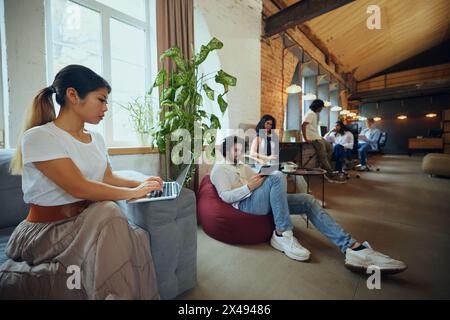Young entrepreneurs and students in co-working space working and cooperating. Cozy, comfortable professional atmosphere Stock Photo