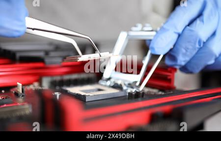 Close-up of workers hands repair computer. Man putting cpu on motherboard. Macro shot of intel microprocessor in the socket. Upgrade and technology co Stock Photo