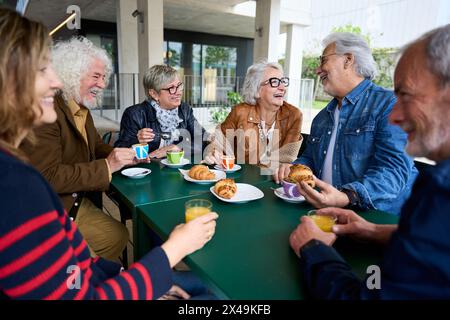 Mature gray hair friends group at coffee bar rooftop. Senior citizens people talking and having fun Stock Photo