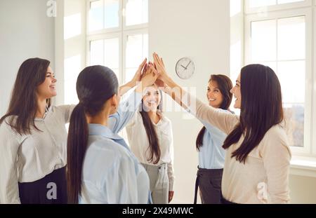 Smiling happy business people women putting their arms together in a stack. Stock Photo