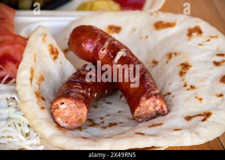 Tortilla wrap, a delightful fusion of savory sausages, crispy French fries, fresh green salad, juicy tomatoes, zesty onions, and shredded cabbage Stock Photo