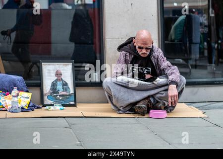 LONDON- APRIL 4th, 2024: A homeless man with a cat on Oxford Street in the West End Stock Photo