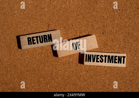 Return of investment words written on wooden blocks with brown background. Conceptual return of investment symbol. Copy space. Stock Photo