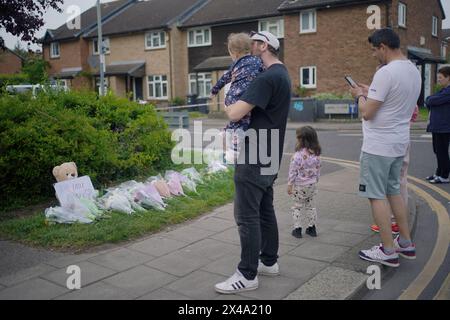Members of the public look at the flowers laid on the corner of Laing Close in Hainault, north-east London, where a 14-year-old boy, named locally as Daniel Anjorin, was killed in a sword attack on Tuesday that saw four others injured, including two Metropolitan Police officers. The teenager, who was fatally injured as he walked to school in Hainault, east London, on Tuesday morning, was a pupil at the same school as Grace O'Malley-Kumar, who was stabbed to death in Nottingham last year. Picture date: Wednesday May 1, 2024. Stock Photo