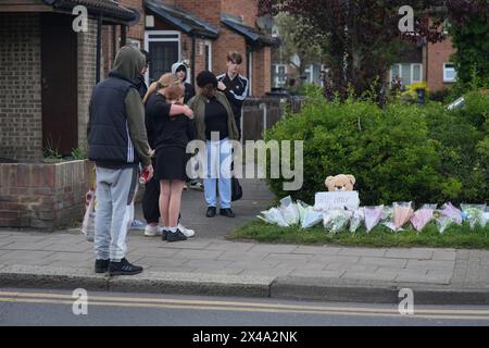 Members of the public look at the flowers laid on the corner of Laing Close in Hainault, north-east London, where a 14-year-old boy, named locally as Daniel Anjorin, was killed in a sword attack on Tuesday that saw four others injured, including two Metropolitan Police officers. The teenager, who was fatally injured as he walked to school in Hainault, east London, on Tuesday morning, was a pupil at the same school as Grace O'Malley-Kumar, who was stabbed to death in Nottingham last year. Picture date: Wednesday May 1, 2024. Stock Photo
