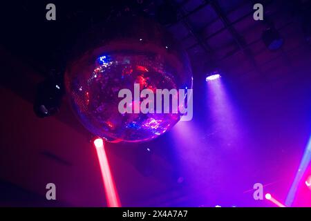 Red and blue colored lights move to the rhythm of the music on the ceiling of a nightclub or concert hall, creating a festive dance atmosphere Stock Photo
