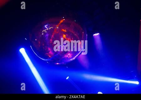 Red and blue colored lights move to the rhythm of the music on the ceiling of a nightclub or concert hall, creating a festive dance atmosphere Stock Photo