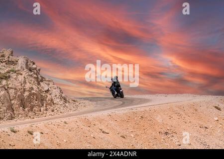 Two lovers on a motorbike coming round a bend in the road Stock Photo