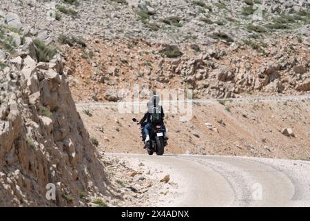 Two lovers on a motorbike coming round a bend in the road Stock Photo