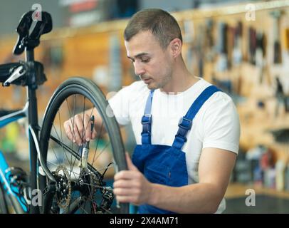 Young male worker oiling bicycle wheel Stock Photo